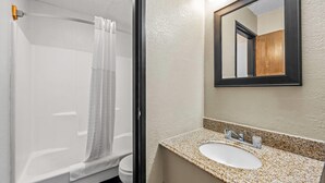 Une salle de bain équipée d’une douche, de toilettes et d’un lavabo avec un miroir.