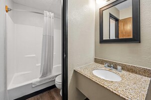 Baño con ducha, inodoro y lavabo con espejo.