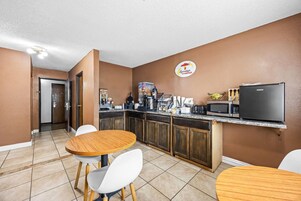 Cocina compacta con cartel de desayuno, un refrigerador, microondas y cafetera.
