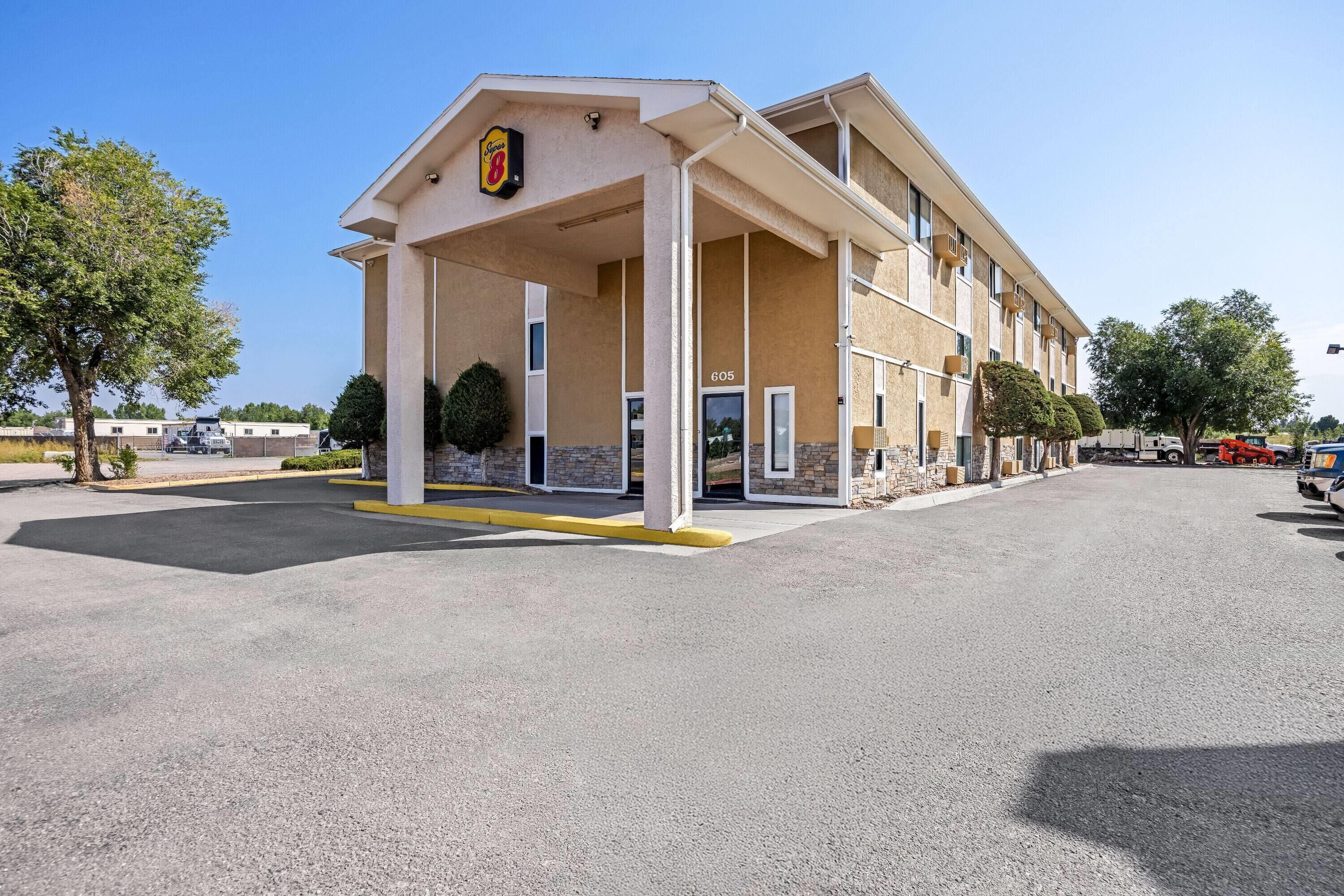A motel with a covered entrance, multiple rooms, and a parking lot.