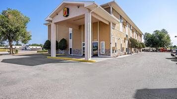 A motel with a covered entrance, multiple rooms, and a parking lot.