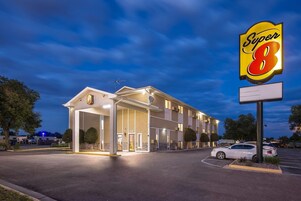 Un hotel Super 8 con una entrada bien iluminada, un estacionamiento y un cartel grande.