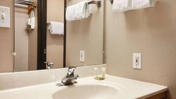 A bathroom with a large mirror, a sink, and a towel rack.