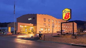 Un hotel Super 8 con una señal de límite de velocidad de 25 millas por hora, un asta de bandera y una entrada bien iluminada.
