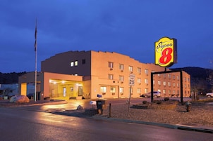 Un hotel Super 8 con una señal de límite de velocidad de 25 millas por hora, un asta de bandera y una entrada bien iluminada.
