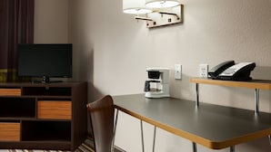 Habitación de hotel con televisión, cafetera, teléfono y lámpara fijada a la pared.