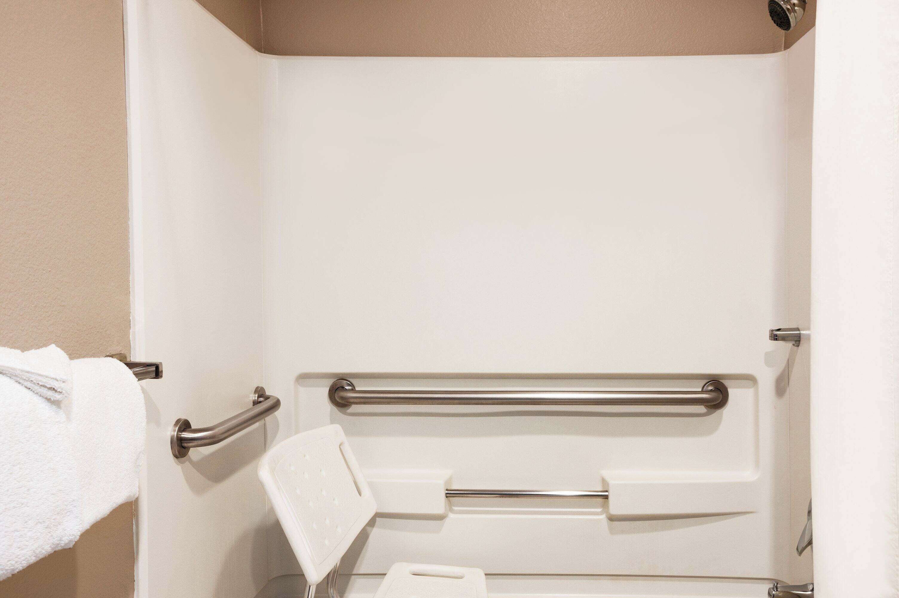 A bathroom with a white bathtub, a towel rack, and a grab bar.