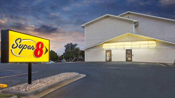 Ein Super 8 Hotel mit großer Beschilderung, einem Parkplatz und einem Gebäude mit flachem Dach und beleuchtetem Eingang.