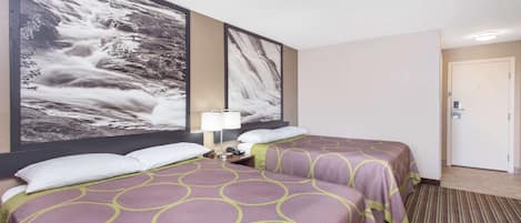 A hotel room with two beds, a large wall-mounted picture of a waterfall, a bedside table with a lamp, and a door to the right.