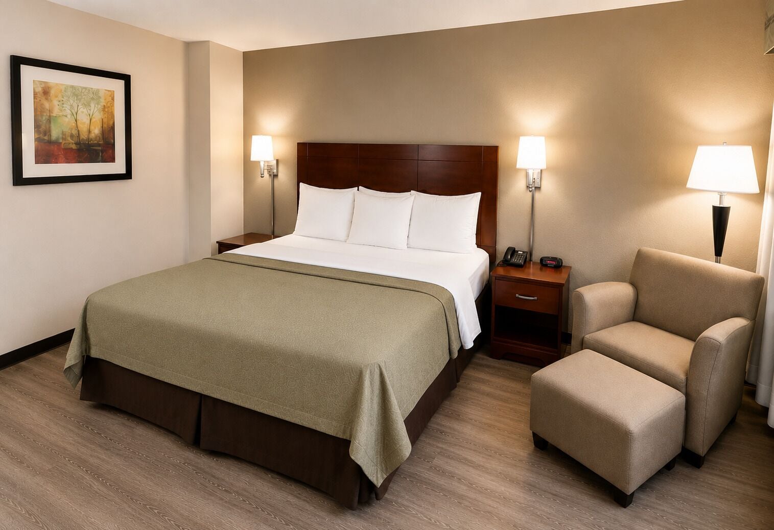 Una habitación de hotel con una cama grande, una silla, una mesita de noche y una lámpara.