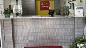 A reception desk with a clock, a 'EcoLodge' sign, a payment terminal, and a phone. - Econo Lodge Cartersville-Emerson Lake Point (Cartersville)
