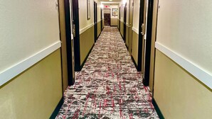 A hotel hallway with carpeted floors, doors on both sides, and a staircase at the end. - Econo Lodge Cartersville-Emerson Lake Point (Cartersville)