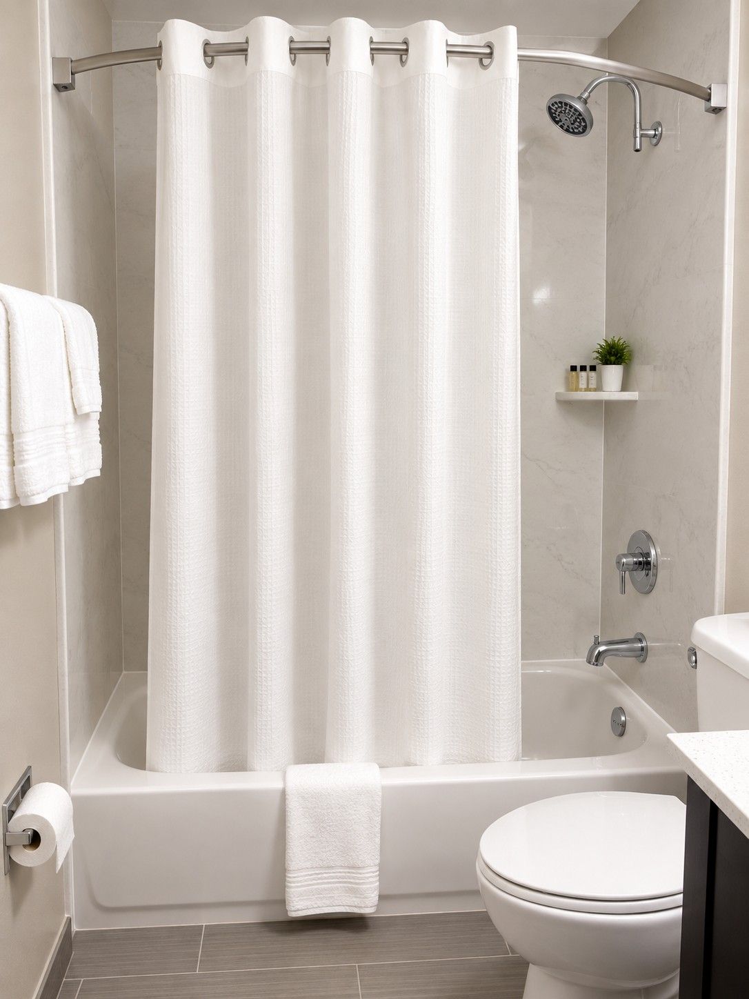 A bathroom with a bathtub, toilet, shower, and a towel rack.