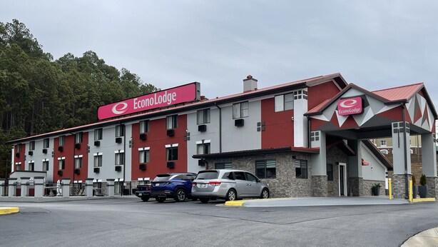 A hotel with a red and white facade, multiple windows, and a parking lot with several cars. - Econo Lodge Cartersville-Emerson Lake Point (Cartersville)