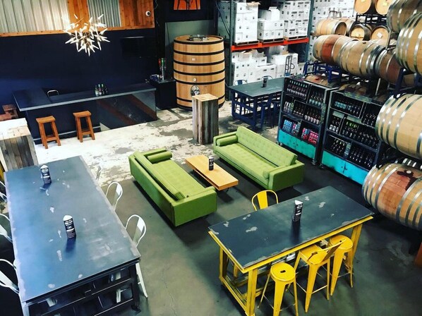 A bar area with wooden barrels, green sofas, and yellow stools. - Econo Lodge Cartersville-Emerson Lake Point (Cartersville)