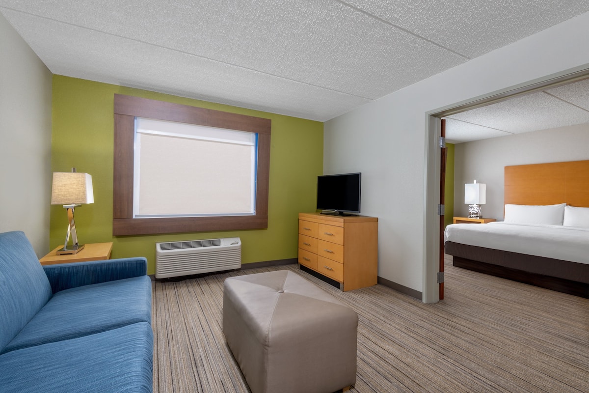 A hotel room with a bed, a TV, a desk, a chair, and a window.