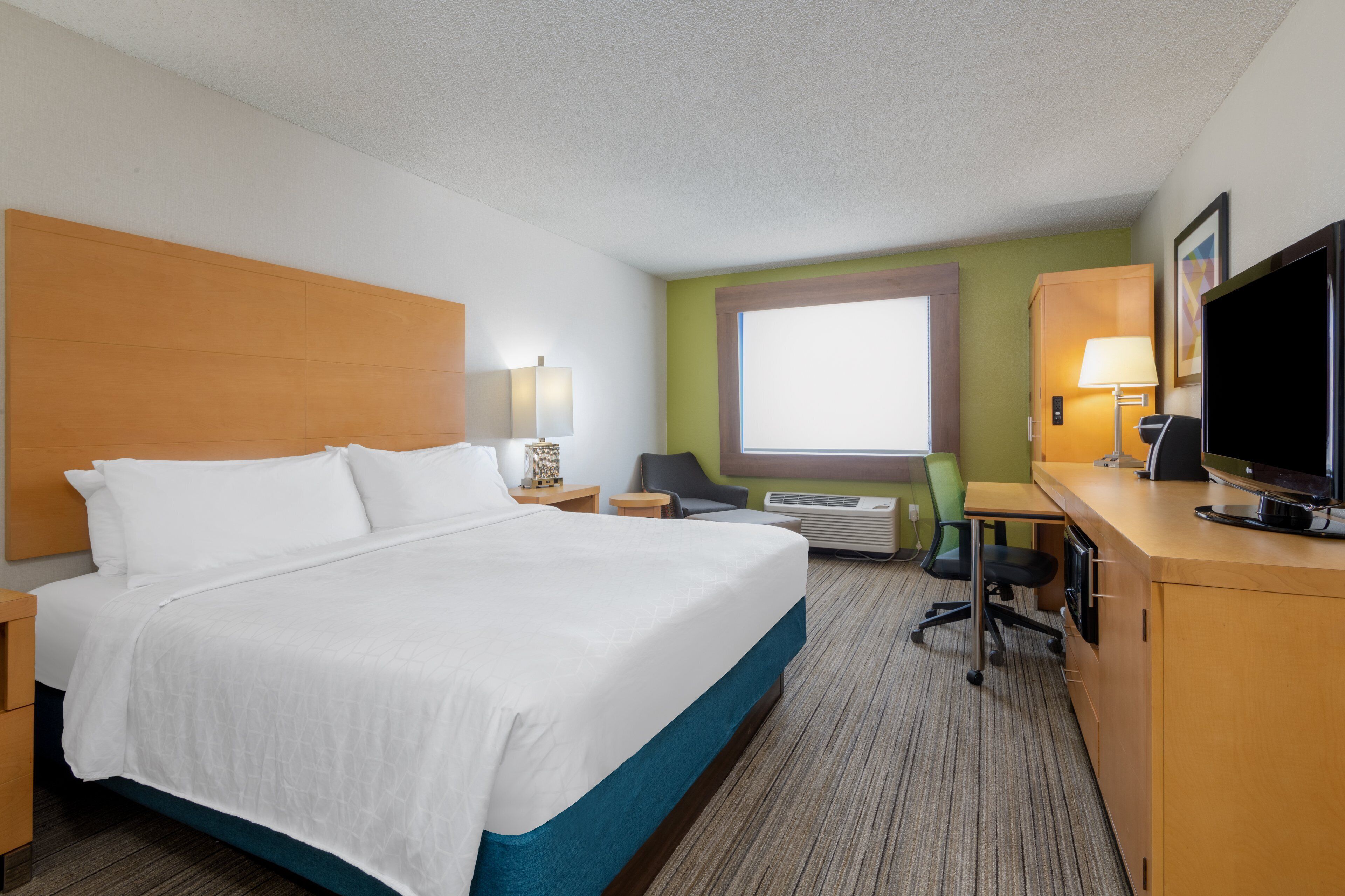 Une chambre d’hôtel avec un lit, un bureau, une télévision et une fenêtre.