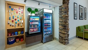 A modern interior with vending machines, a stone pillar, and a green sofa.