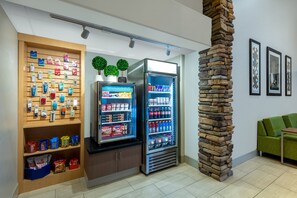 A modern interior with vending machines, a stone pillar, and a green sofa. - Holiday Inn Express & Suites Wheat Ridge-Denver West by IHG (Wheat Ridge)