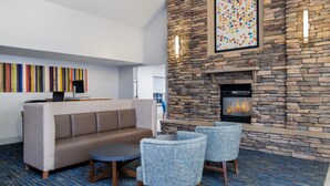 A modern lounge area with a stone fireplace, a sofa, and two armchairs.