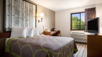 Una camera d'albergo con un letto grande, una scrivania, una televisione e una finestra con tende.