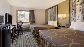 A hotel room with two beds, a desk with a television, a chair, a window with curtains, and a wall-mounted lamp.