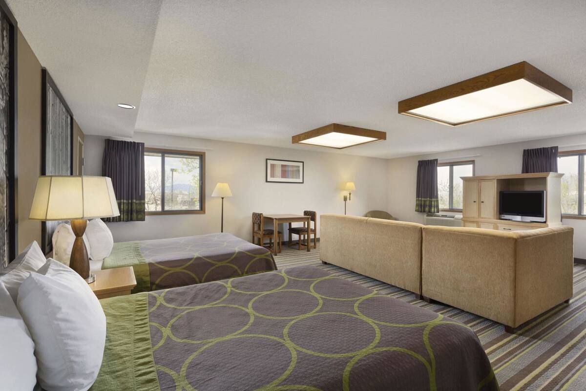 Una habitación de hotel con dos camas, un escritorio, un televisor y una ventana.