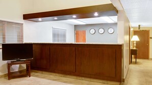 Un coin cuisine avec un comptoir en bois, un téléviseur posé sur un meuble et une horloge au mur.