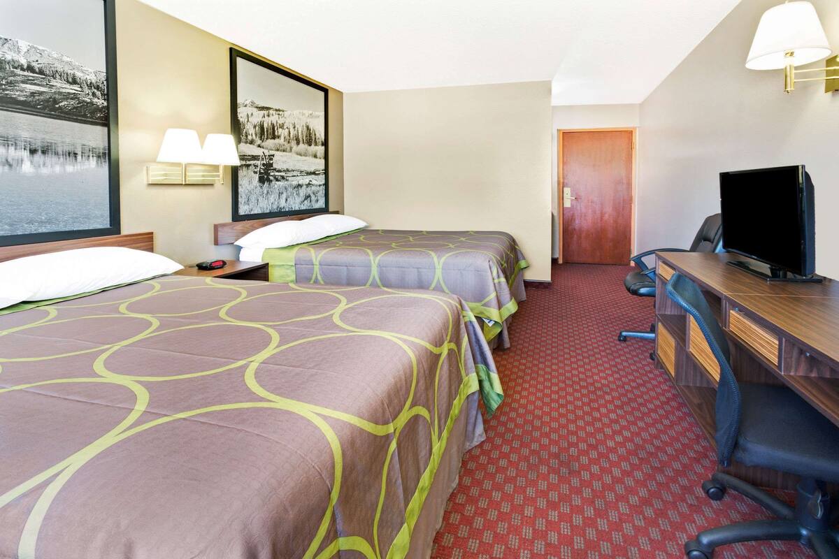 Una habitación de hotel con dos camas, un escritorio con ordenador y una televisión.