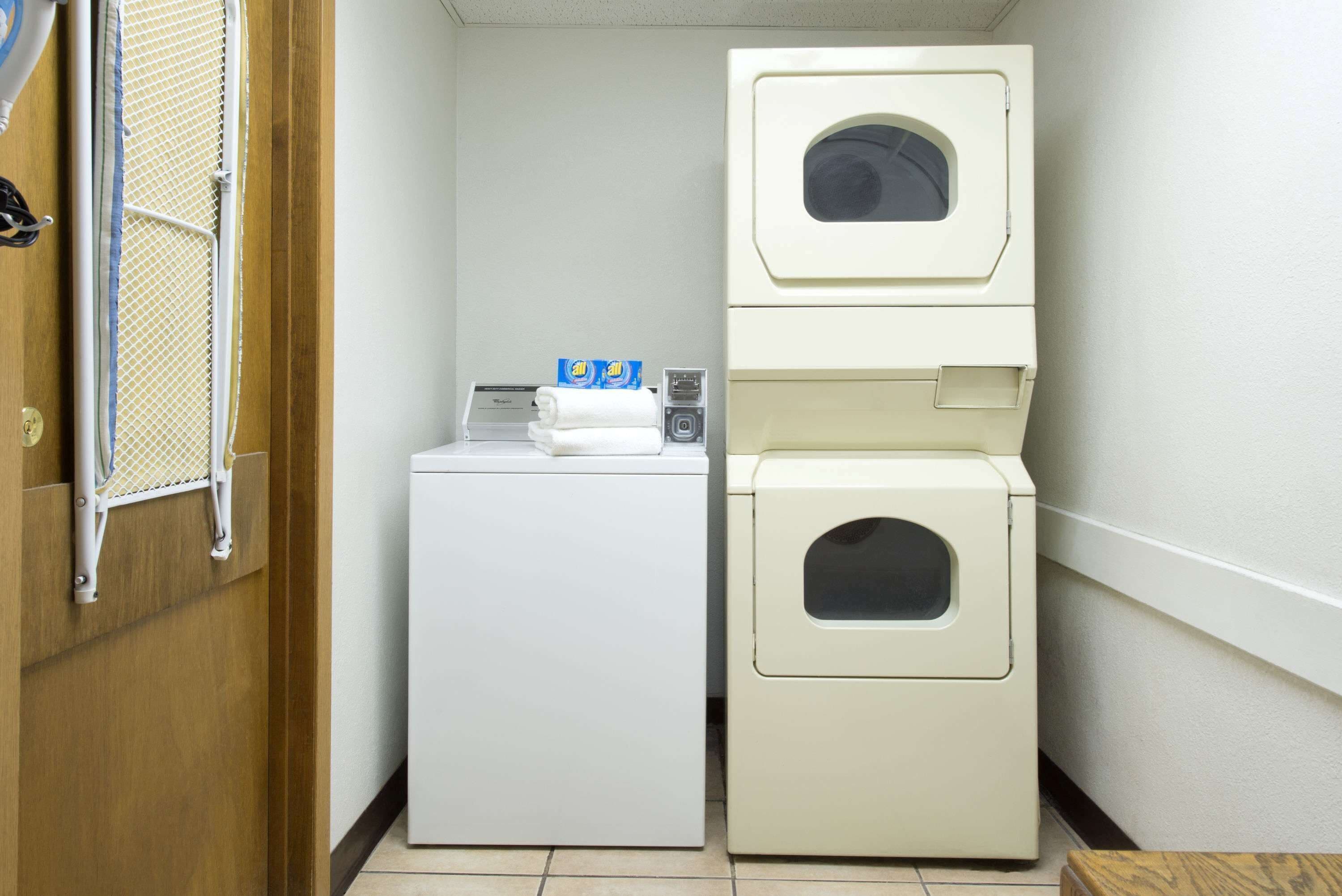 Een wasserette met een voorlader wasmachine en een gestapelde bovenlader droger.