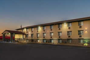 Un hotel de varios pisos con techo plano, entrada cubierta y estacionamiento.