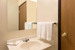Un baño con lavamanos, espejo y barra para toallas.