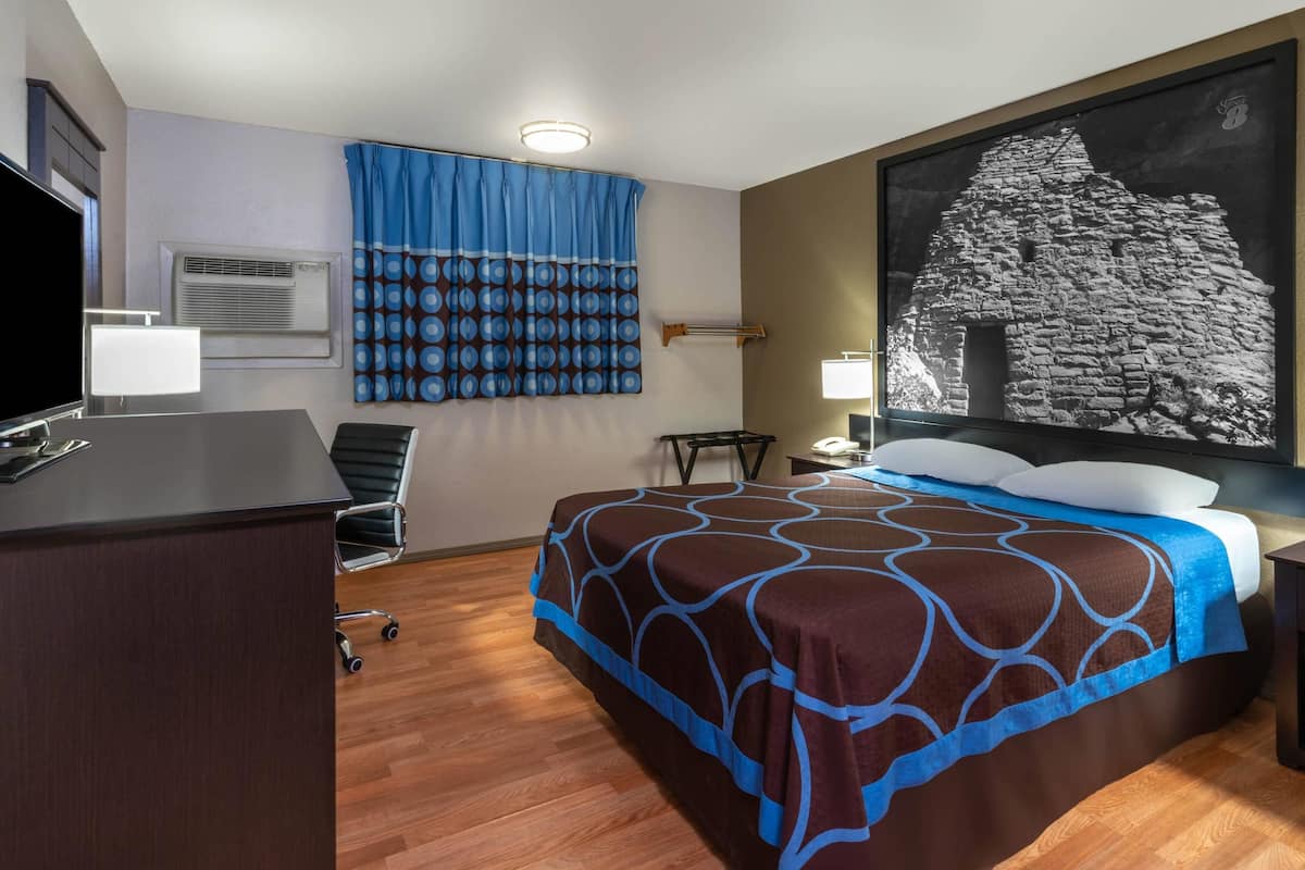 Ein Hotelzimmer mit Bett, Schreibtisch, Stuhl und einem großen Wandbild.