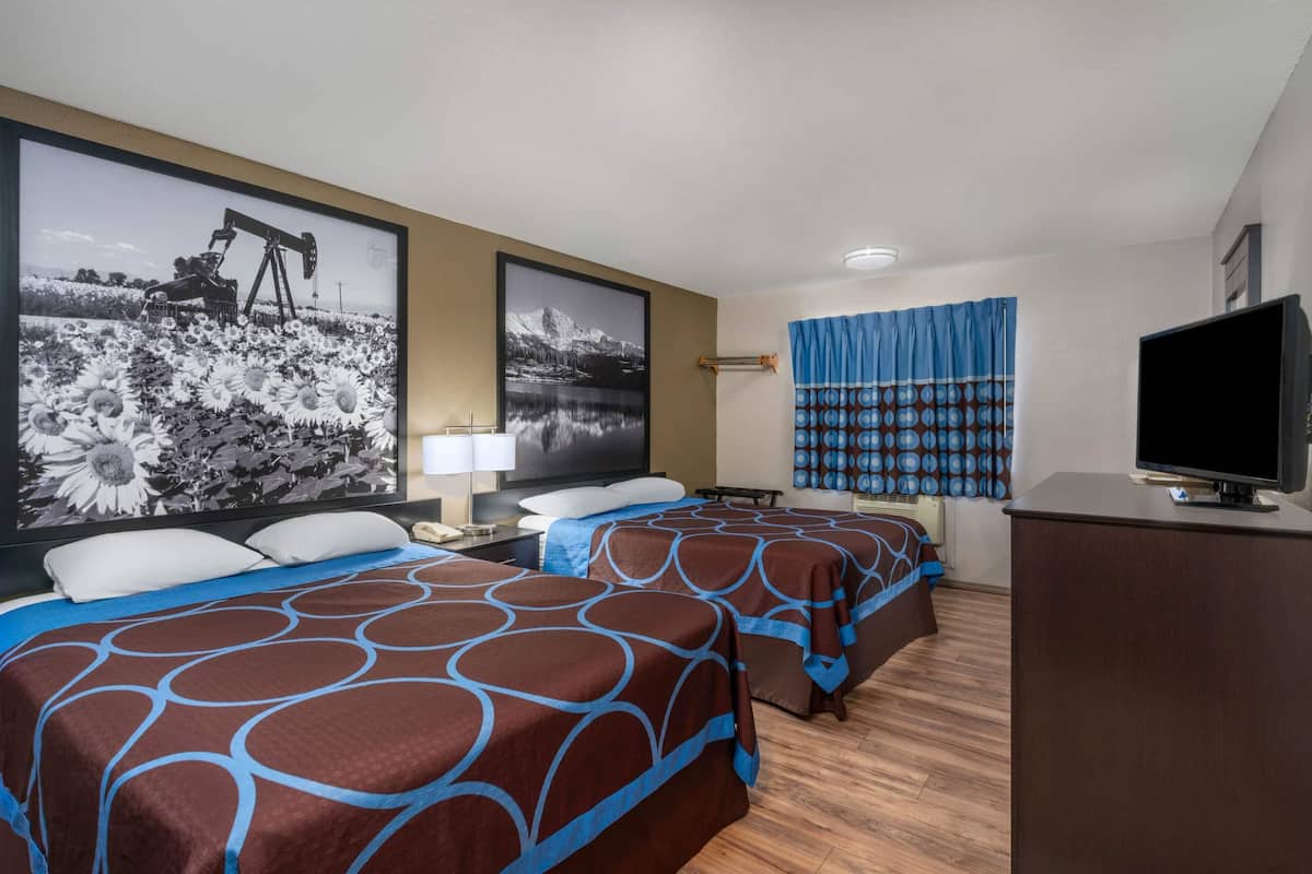Ein Hotelzimmer mit zwei Betten, einem Fernseher und Bildern an der Wand.