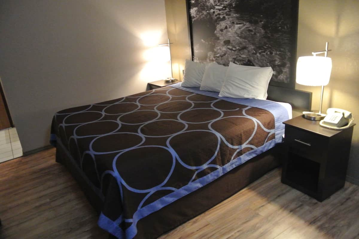 Ein Hotelzimmer mit einem Bett, Nachttischen und einer Wand mit strukturierter Gestaltung.
