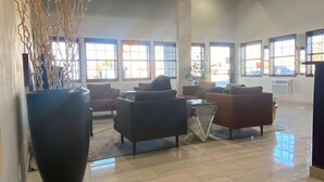 A spacious lobby with multiple seating areas, large windows, and a tall pillar.