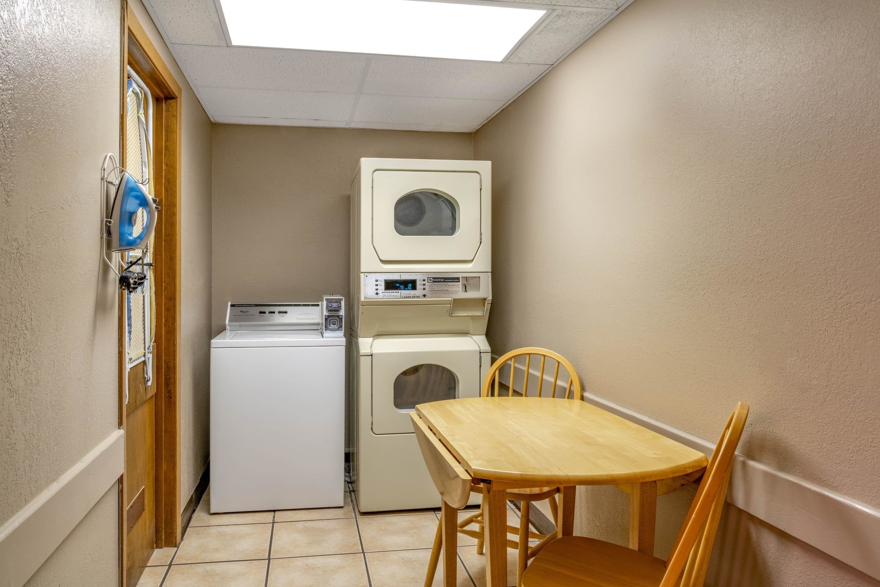 A laundry area with a washing machine, dryer, and ironing board.