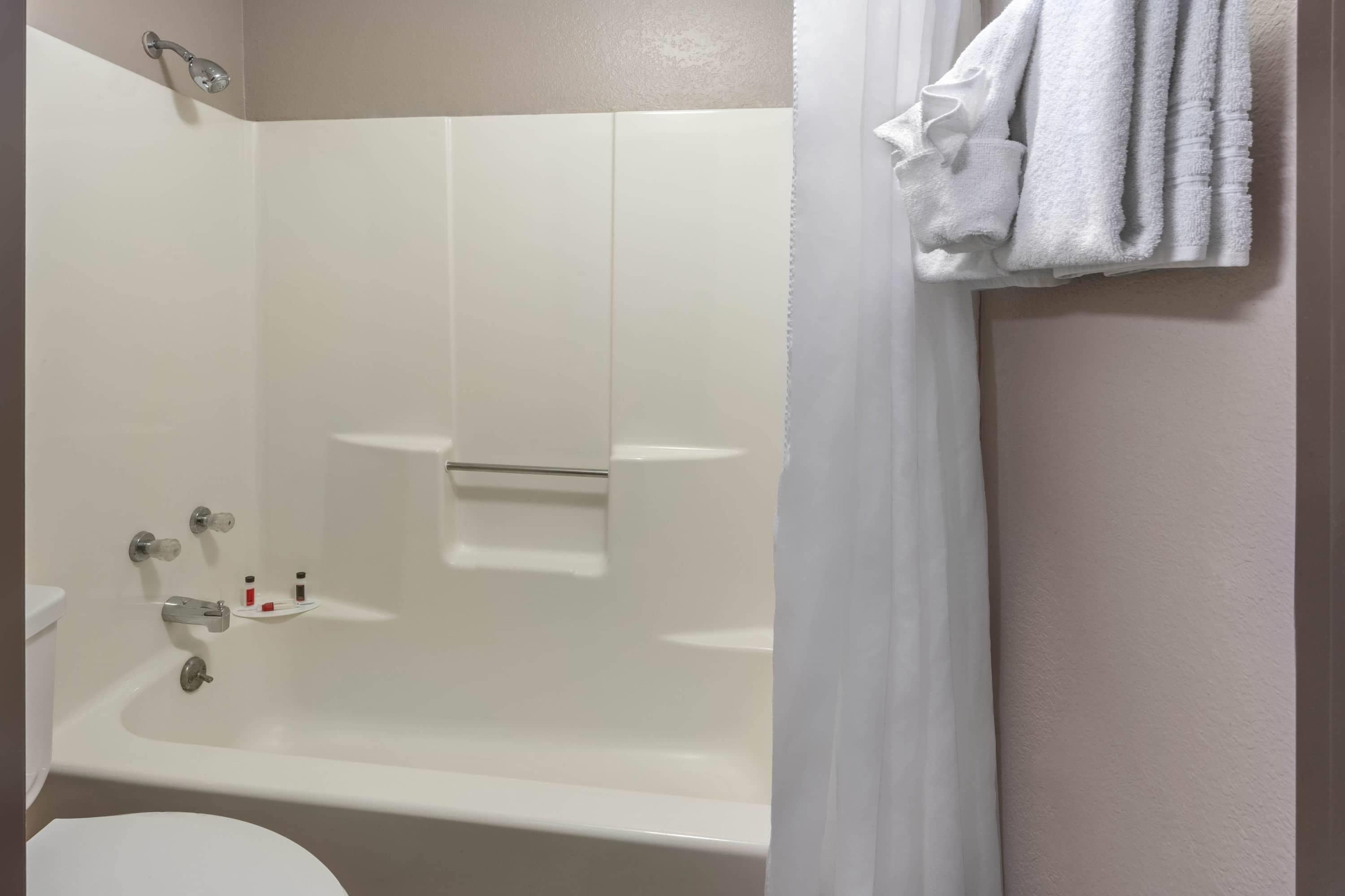 A bathroom with a bathtub, a shower, and a toilet. There are towels hanging on the wall.