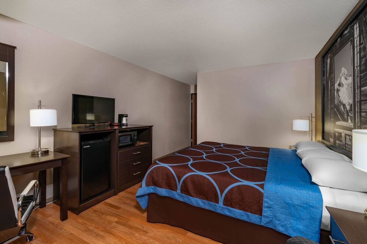 Ein Hotelzimmer mit einem Bett, einem Schreibtisch mit Fernseher, einer Mikrowelle und einer Kaffeemaschine.