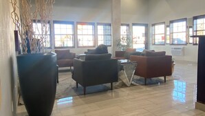 A spacious lobby with a high ceiling, large windows, and a polished floor.