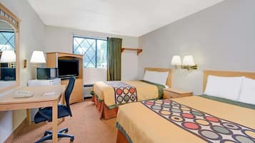 A hotel room with two beds, a desk, a chair, a television, and a window with curtains.