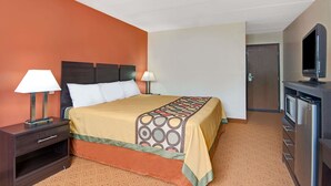 Une chambre d’hôtel avec un lit, une table de chevet, une lampe et un téléviseur posé sur un meuble.