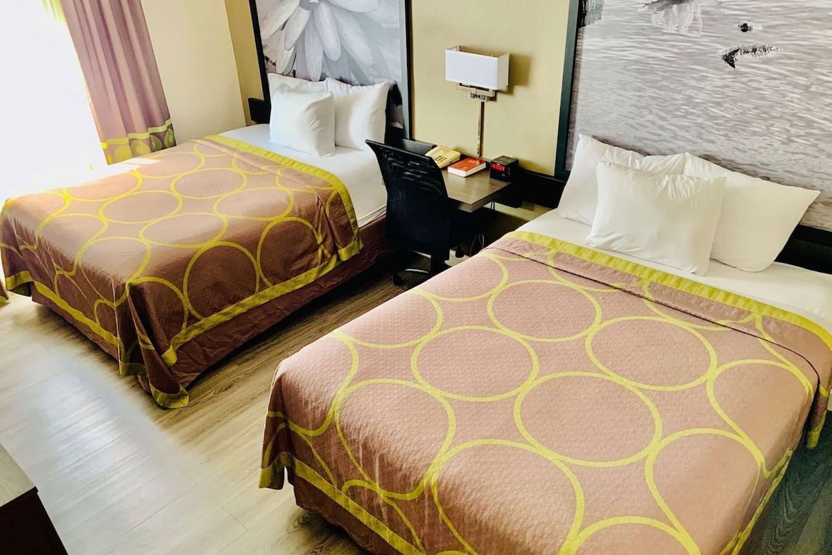 Two beds with matching headboards, a desk with a lamp, and a window with a view of water.