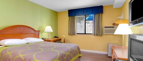 Habitación de hotel con cama, dos mesitas de noche, televisor y ventana con cortinas.