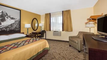 A hotel room with a bed, two bedside tables with lamps, a desk with a chair, a television, and a large window with curtains.
