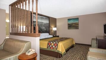 A hotel room with a bed, a chair, a desk, a telephone, a painting, and a staircase.