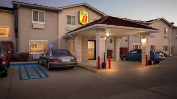 Een hotel met een Super 8 bord, een overdekte ingang en een parkeerplaats voor mensen met een handicap.