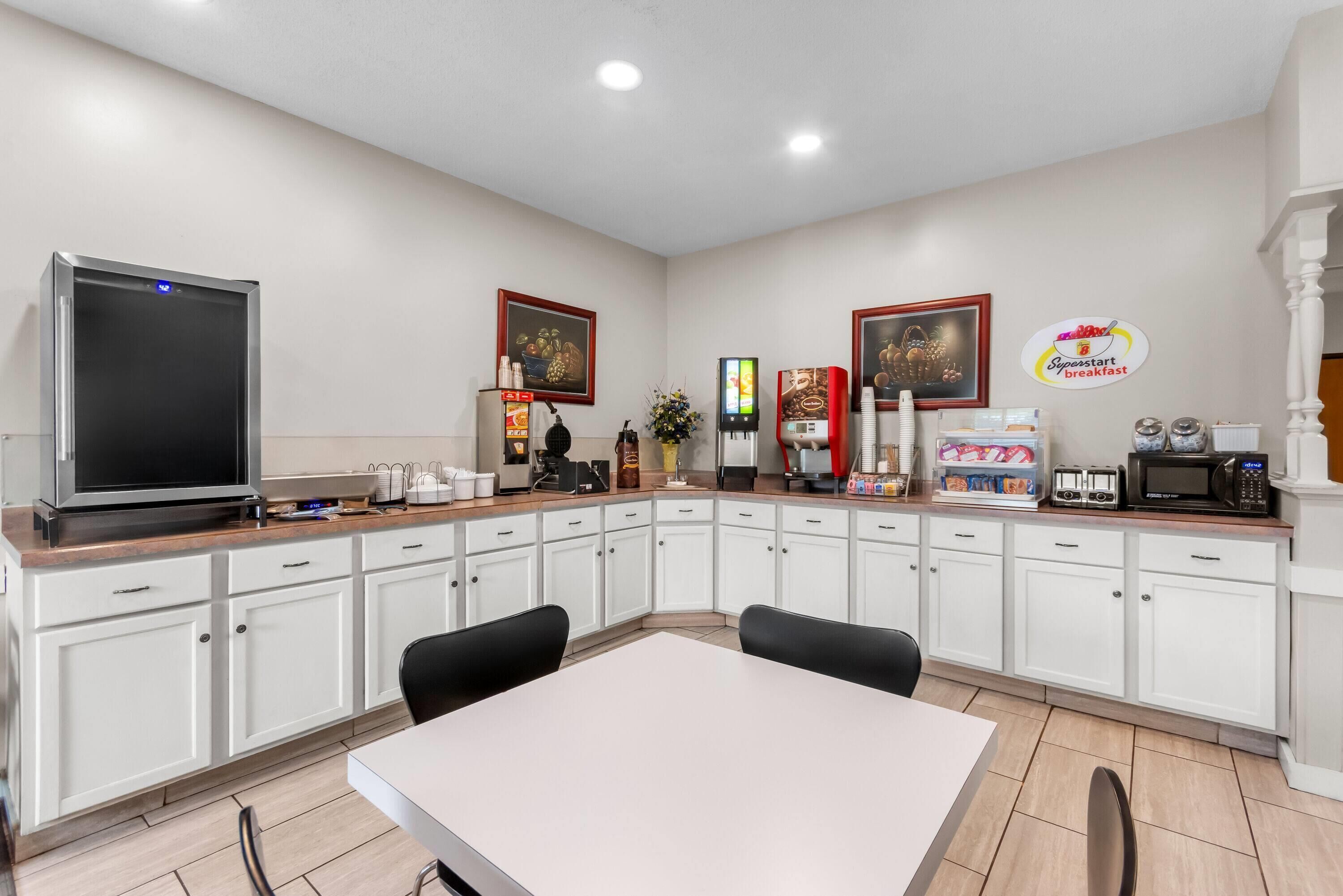 A modern kitchen with white cabinets, a large refrigerator, a microwave, and a coffee machine.