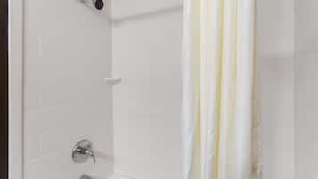 Ducha con azulejos blancos, cortina blanca y cabezal de ducha cromado.