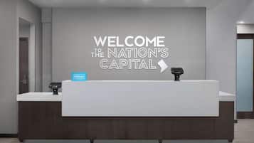 A reception desk with a sign reading "WELCOME TO THE NATION'S CAPITAL" and a Hilton logo.